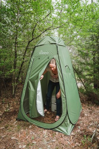 A camping toilet is located within a privacy tent.